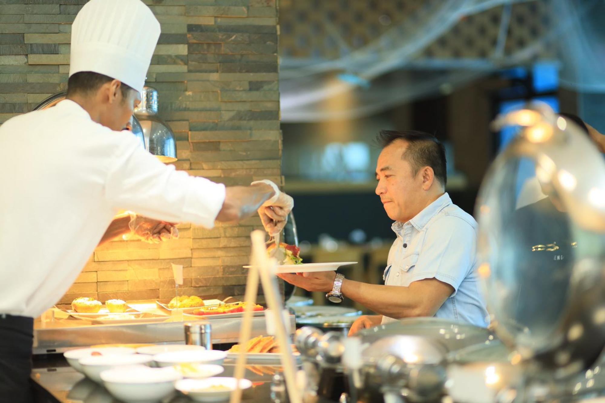 Ramee Grand Hotel And Spa Manama Luaran gambar A chef serving food at a buffet